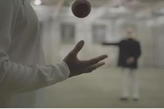 Man in foreground throwing cricket ball