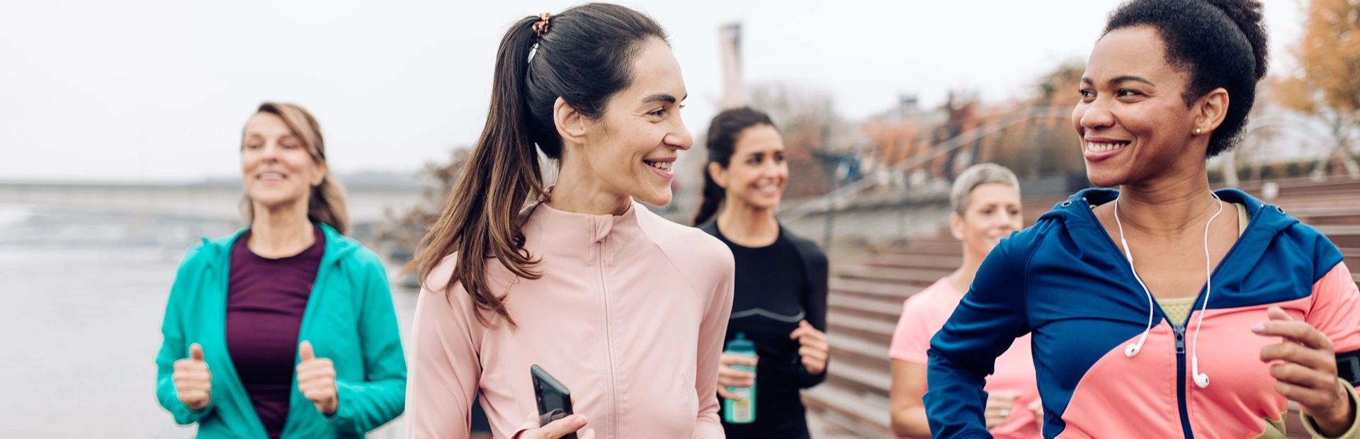Group of Women Jogging by the River on a Cold Day