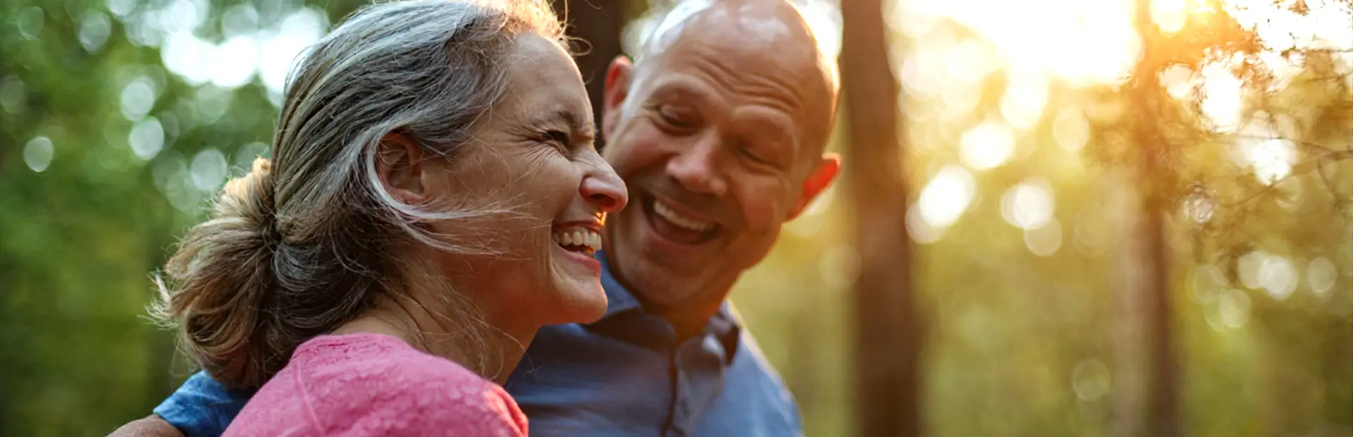 Elderly coupling hugging in sunlit forest