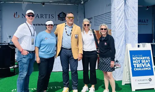 Novartis associates stand near the Numbers Challenge and Hot Seat Trivia Experience