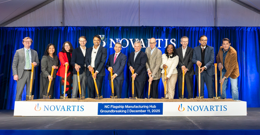 Team shot at the groundbreaking, with shovels in sand. 