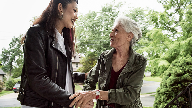 Young woman helping mature adult up stairs 