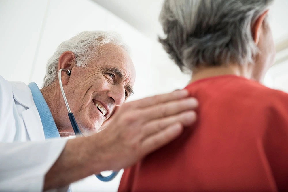 Smiling doctor supporting  female clinical trial participant with a pat on the back