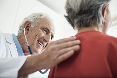 Smiling doctor supporting  female clinical trial participant with a pat on the back