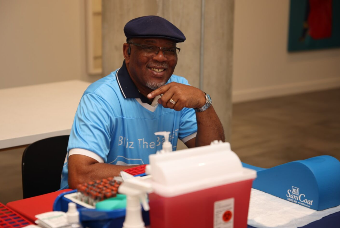 Volunteer at a check-in table working the Blitz the Barriers Screening Event. The event check-in took place in an indoor community setting.