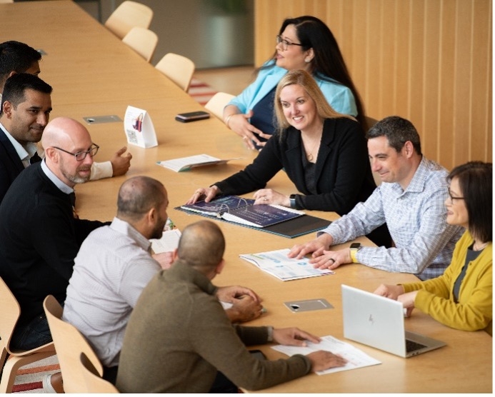 A group of men and women sitting around a conference table, actively participating in a discussion