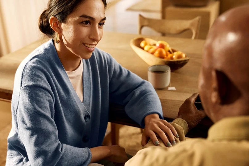 Older adult and caregiver having a comforting conversation at home.