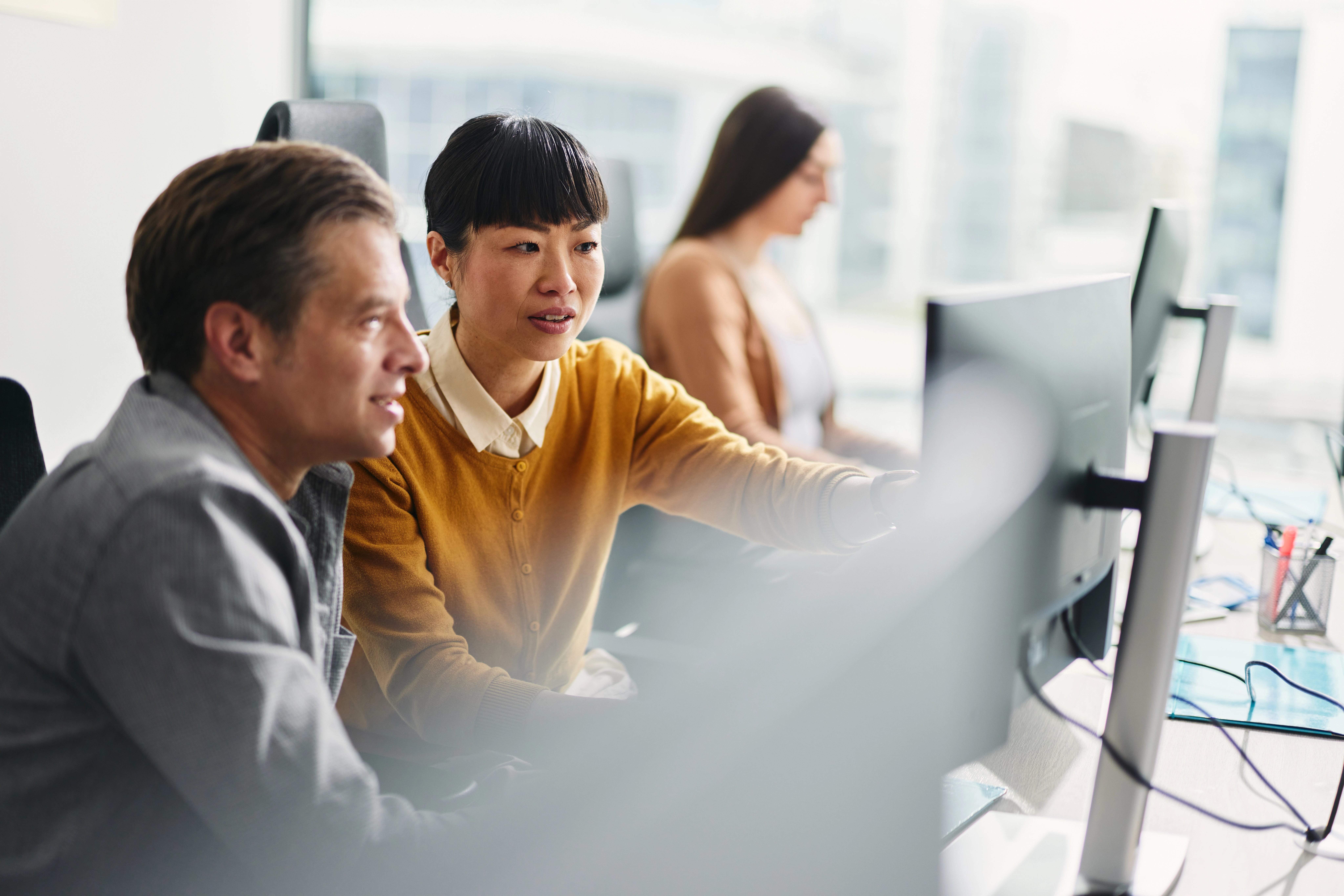 Three people looking at their computer screens at work.