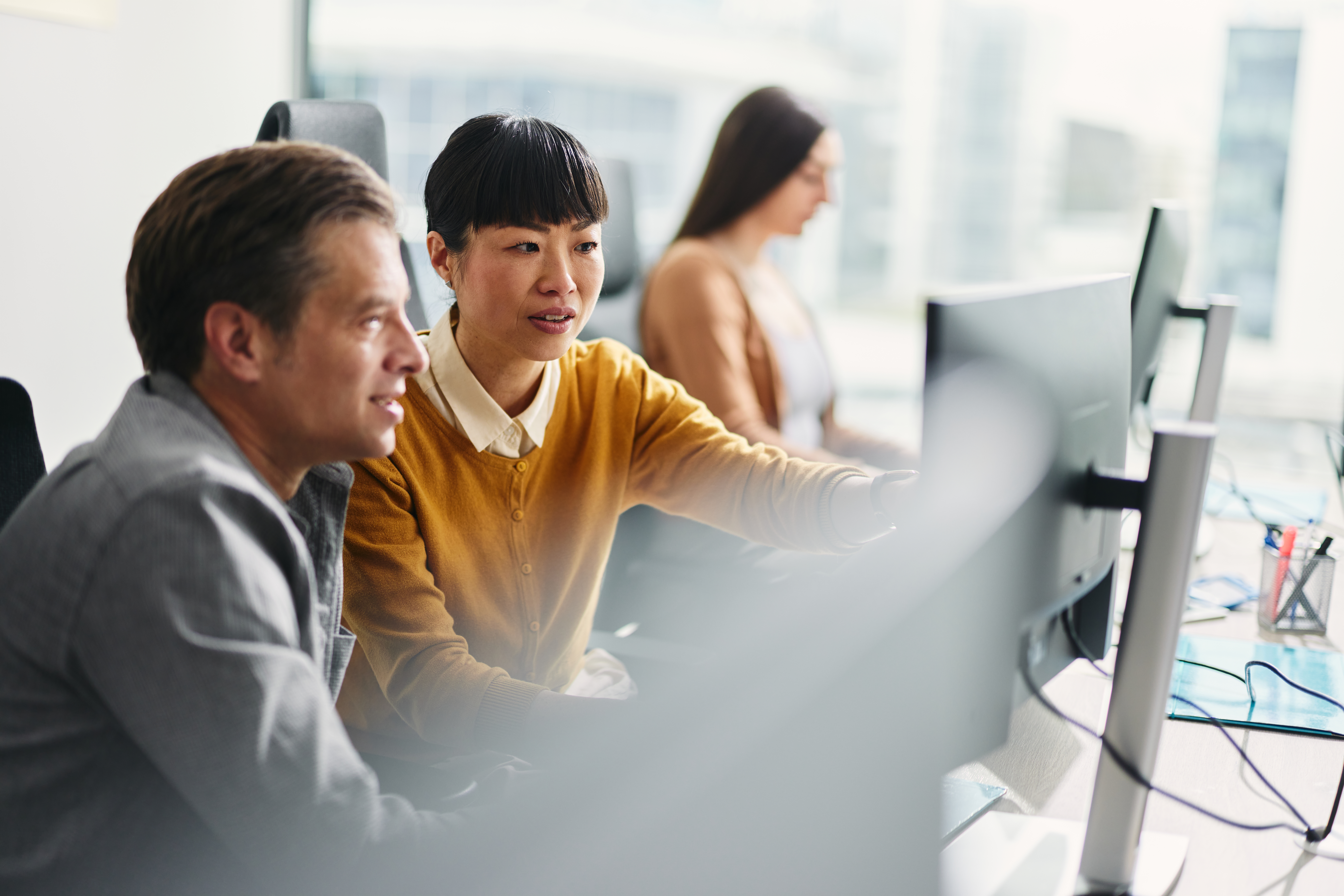 Three people looking at their computer screens at work.