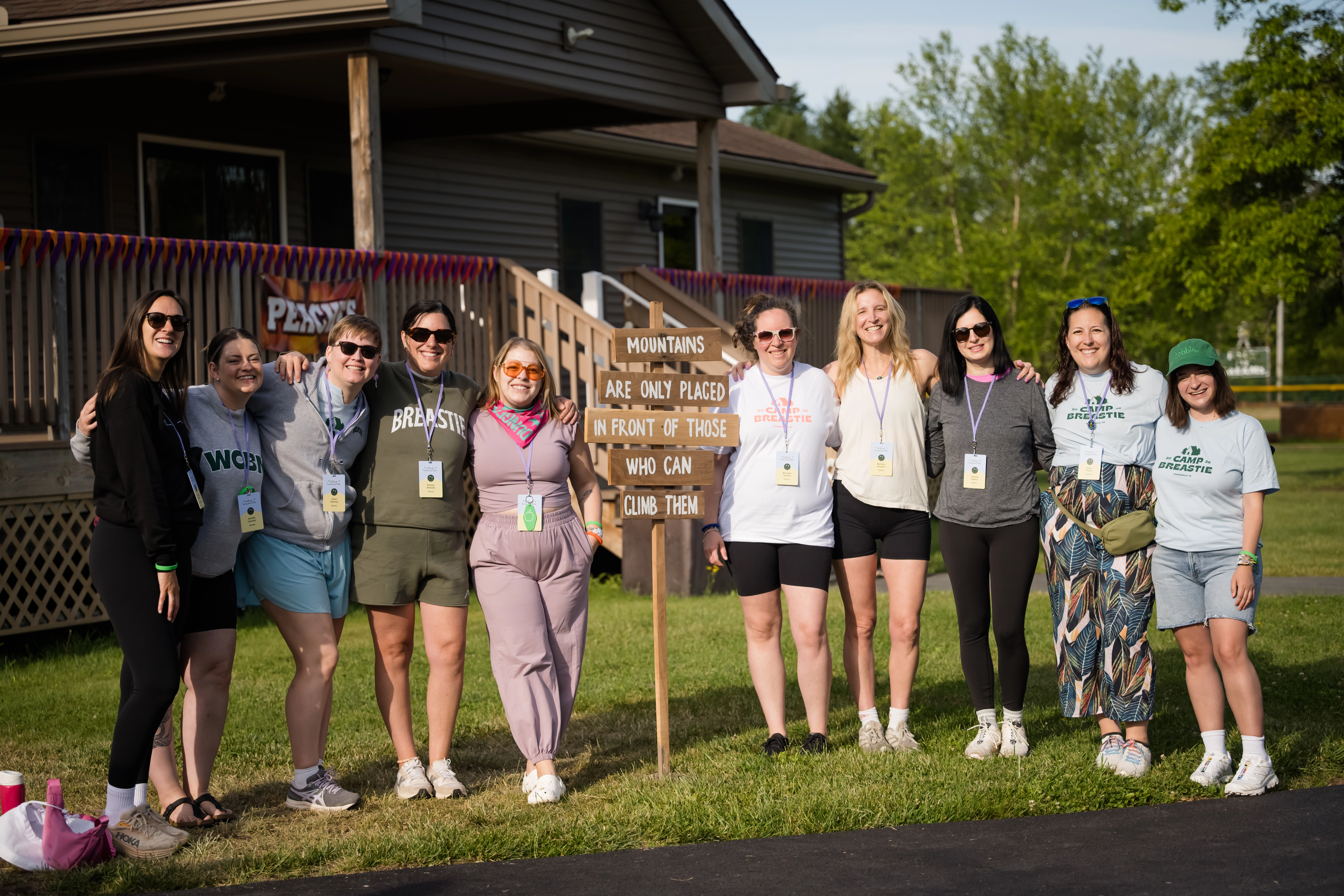 Group of women posing together at Camp Breastie beside an inspirational sign.