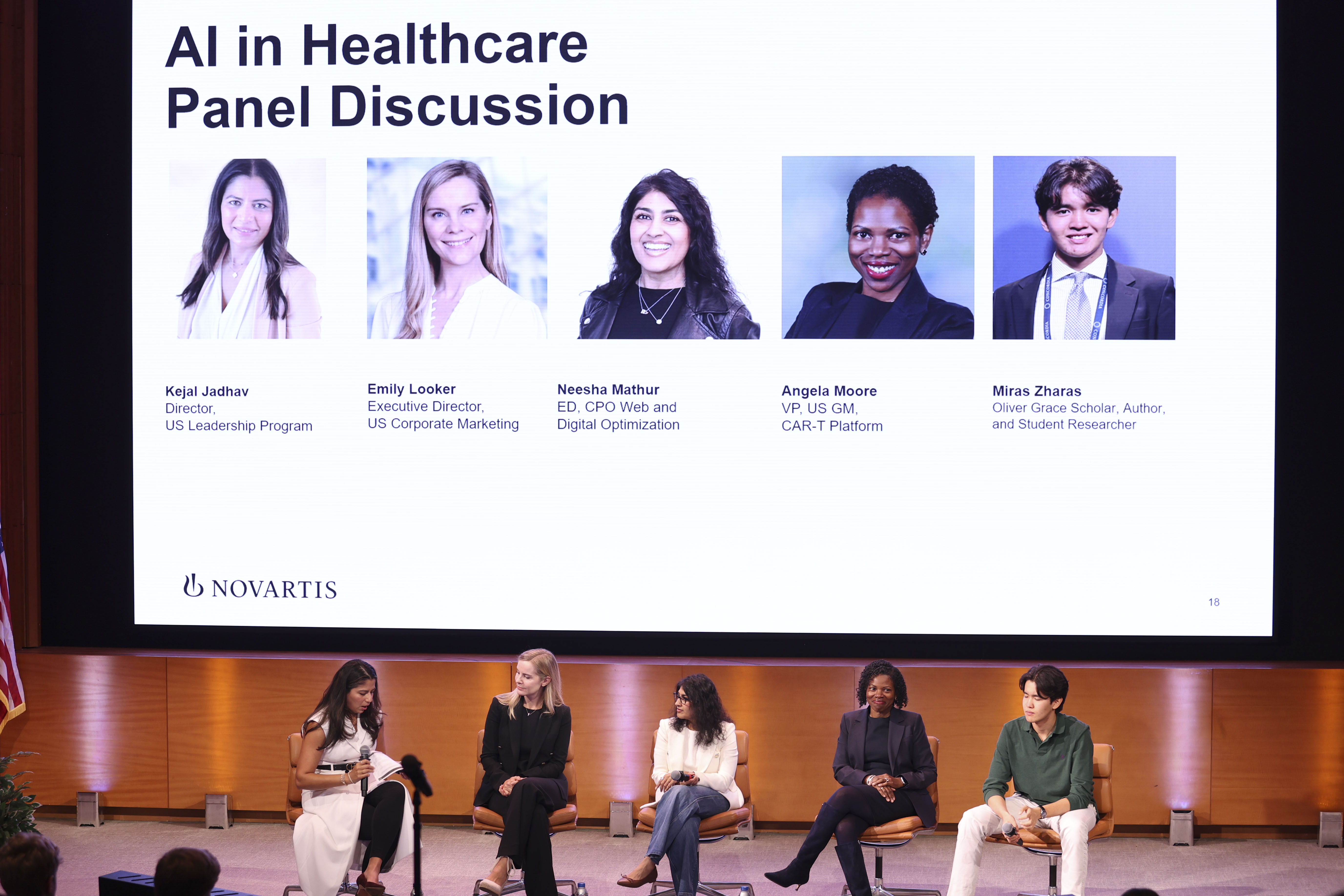 Five people seated onstage beneath a large “AI in Healthcare Panel Discussion” slide showing panelist photos and names.