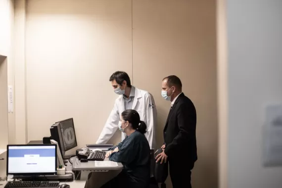 A female healthcare professional sits at a computer as she and two male healthcare professionals review the information on a screen.
