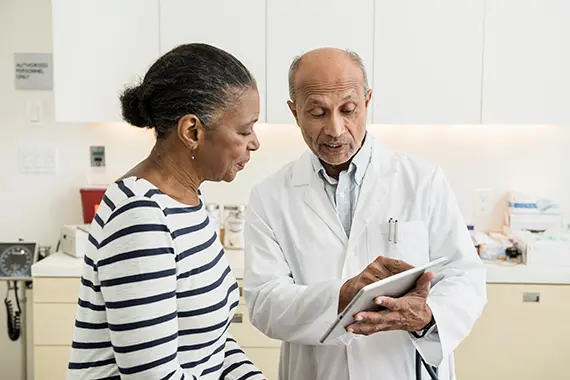 Una mujer y un médico del ensayo clínico revisan diferentes tipos de notas del ensayo clínico