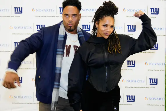 People posing for picture in front of New York Giants background