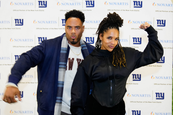 Two people posing in front of New York Giants background