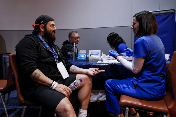 Person seated at table while nurse prepares medical supplies for prostate cancer screening