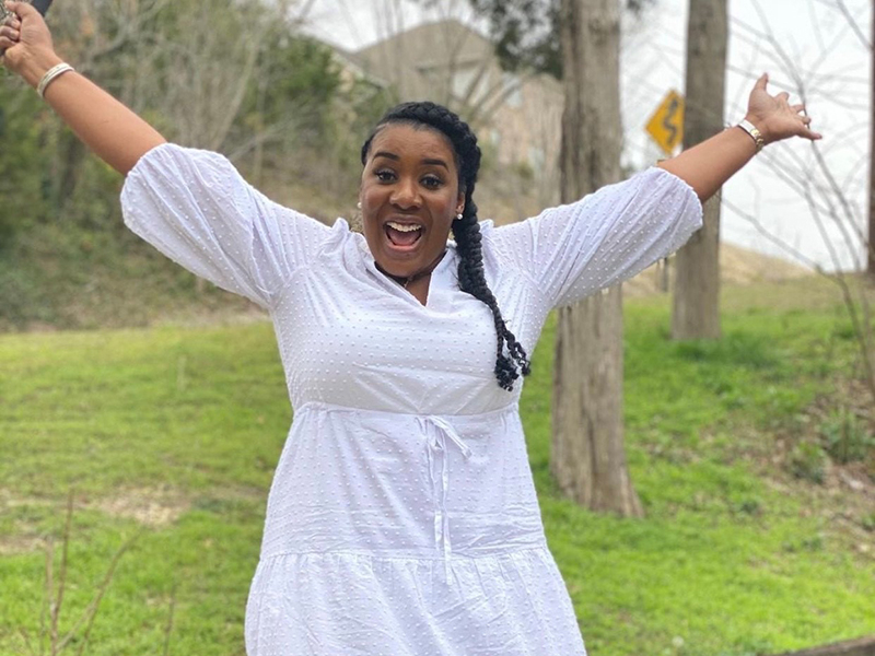ShantaQuilette smiles and extends her arms wide in elation