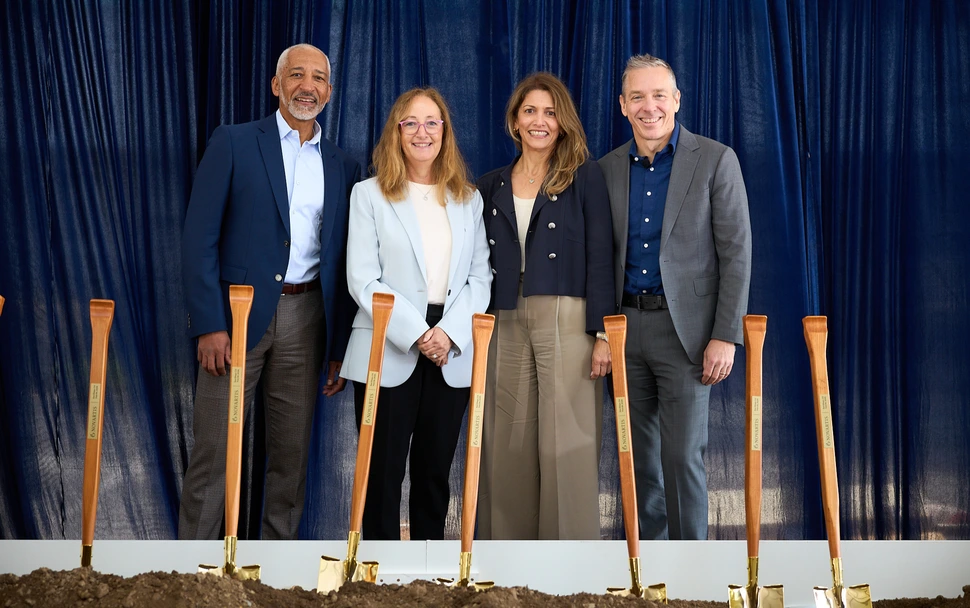 Team shot at the groundbreaking, with shovels in sand. 