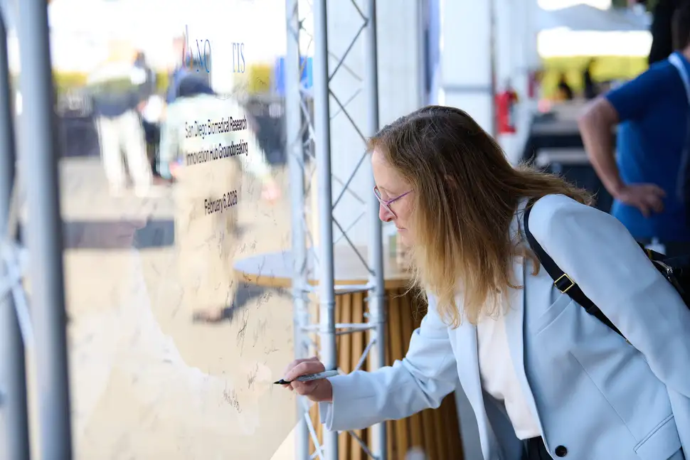 Biomedical Research President Fiona Marshall signing a ceremonial glass pane. 