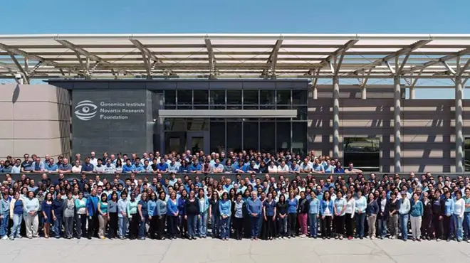 Large group photo of hundreds of Novartis San Diego research associates and scientists gathered in front of the GNF building in 2010
