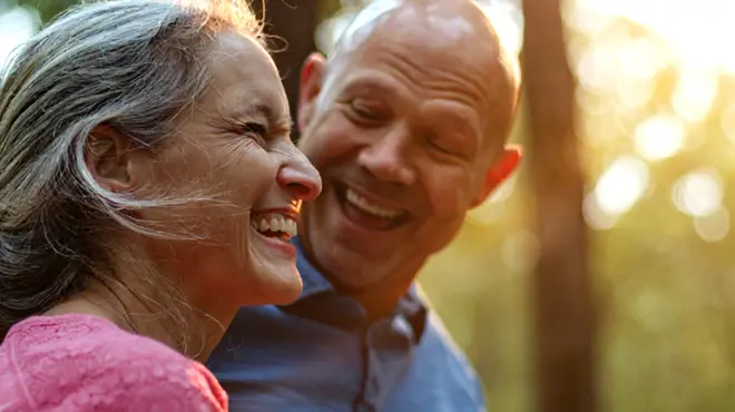 Elderly coupling hugging in sunlit forest